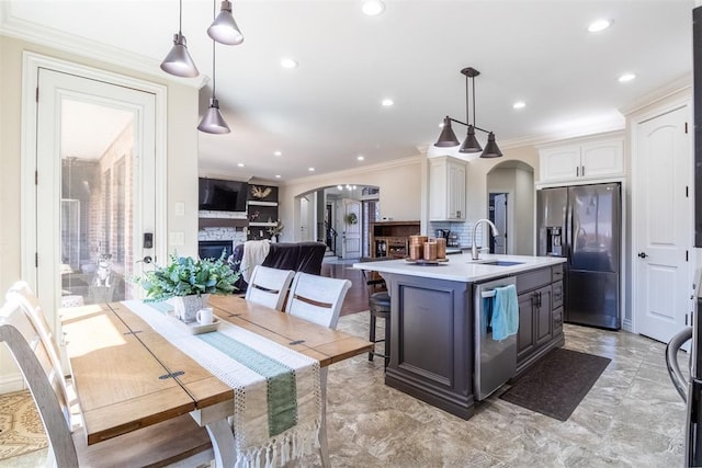 kitchen featuring a sink, arched walkways, appliances with stainless steel finishes, a fireplace, and light countertops