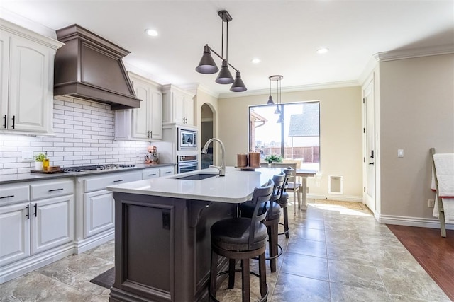 kitchen with ornamental molding, a sink, custom range hood, appliances with stainless steel finishes, and backsplash