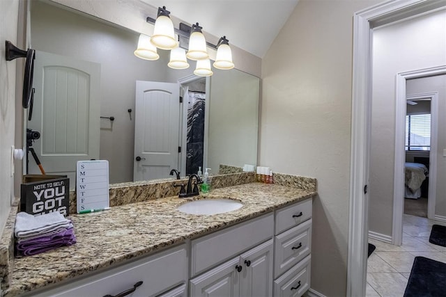 ensuite bathroom featuring vanity, baseboards, tile patterned flooring, vaulted ceiling, and ensuite bathroom