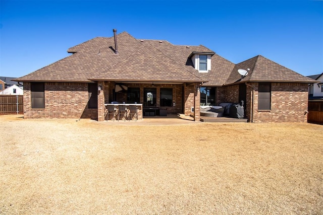 rear view of property featuring a patio, brick siding, outdoor dry bar, and fence