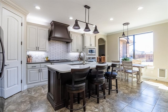 13216 Knight Island Dr, Oklahoma City, OK 73142 - kitchen featuring custom exhaust hood, ornamental molding, backsplash, appliances with stainless steel finishes, and a sink