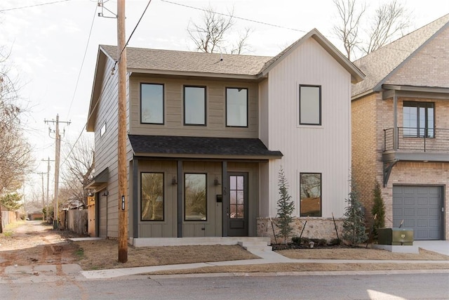 view of property featuring concrete driveway, a garage, board and batten siding, and roof with shingles