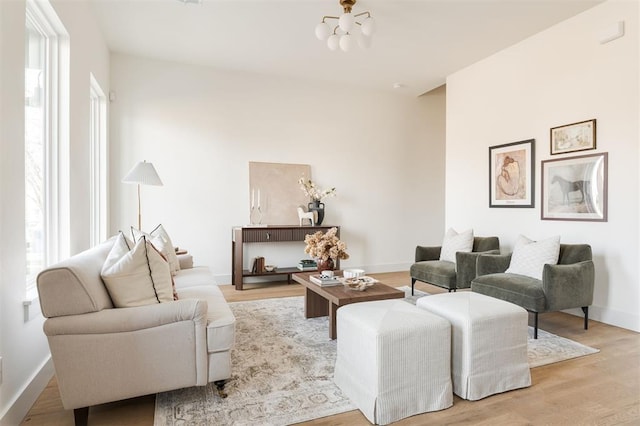 living area featuring baseboards, a notable chandelier, and light wood-style flooring