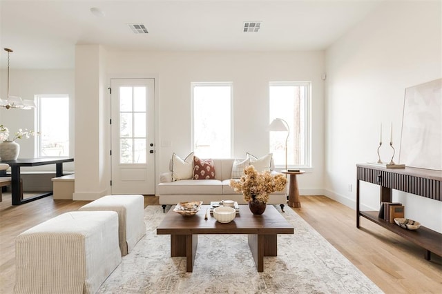 living room with a wealth of natural light, visible vents, and light wood-style flooring
