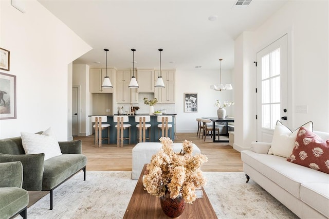 living room with a chandelier, baseboards, and light wood-style floors