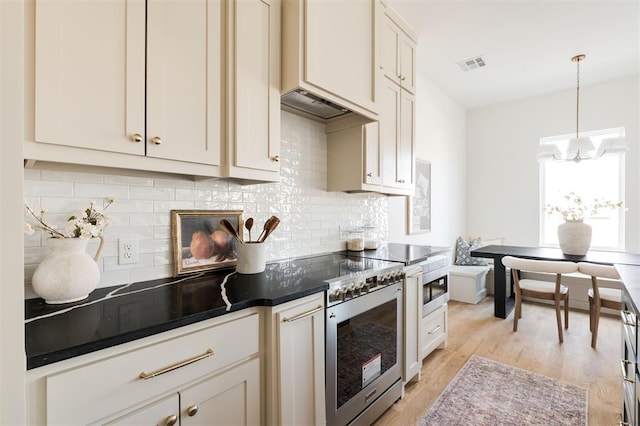 kitchen with high end stove, tasteful backsplash, dark countertops, light wood-style floors, and custom exhaust hood