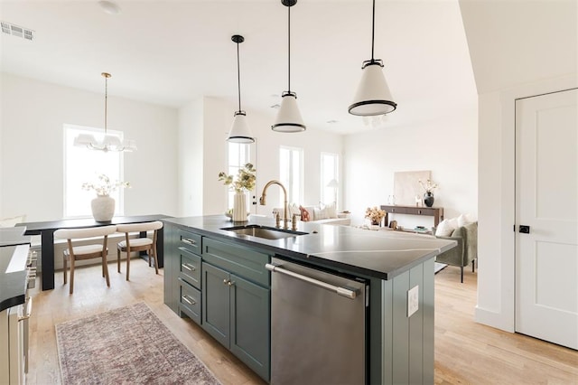 kitchen with dark countertops, light wood finished floors, dishwasher, and a sink
