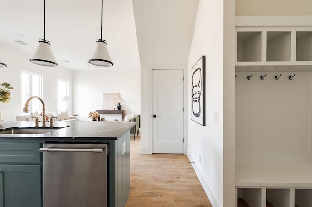 kitchen featuring baseboards, a sink, light wood-style floors, dishwasher, and decorative light fixtures