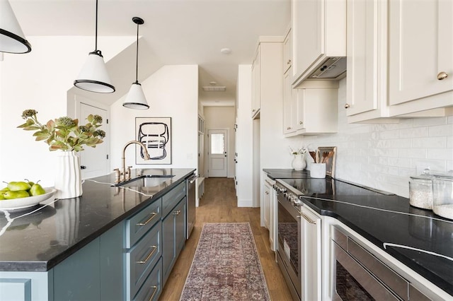 kitchen with a sink, backsplash, wood finished floors, white cabinetry, and stainless steel appliances