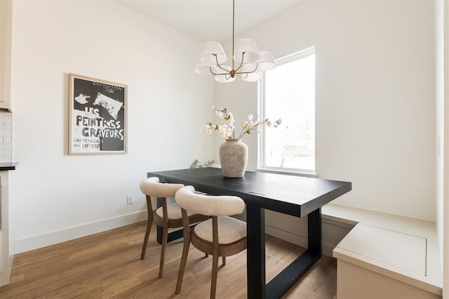 dining space featuring a notable chandelier, baseboards, and wood finished floors
