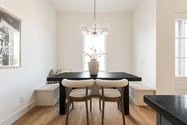 dining room featuring light wood-style flooring, a notable chandelier, and baseboards