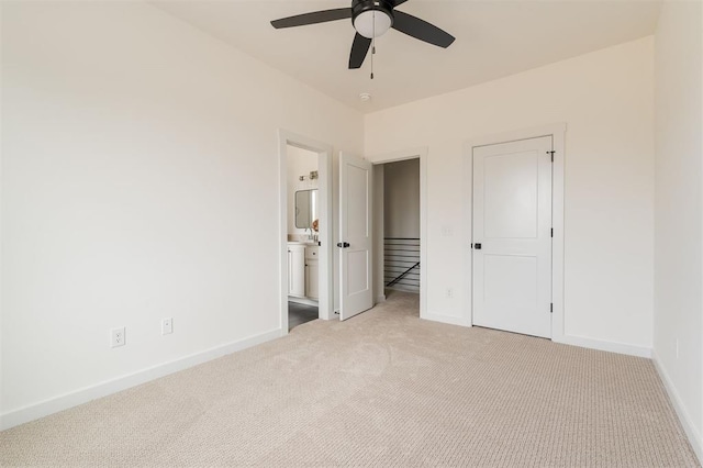 unfurnished bedroom featuring baseboards, light colored carpet, and ensuite bathroom