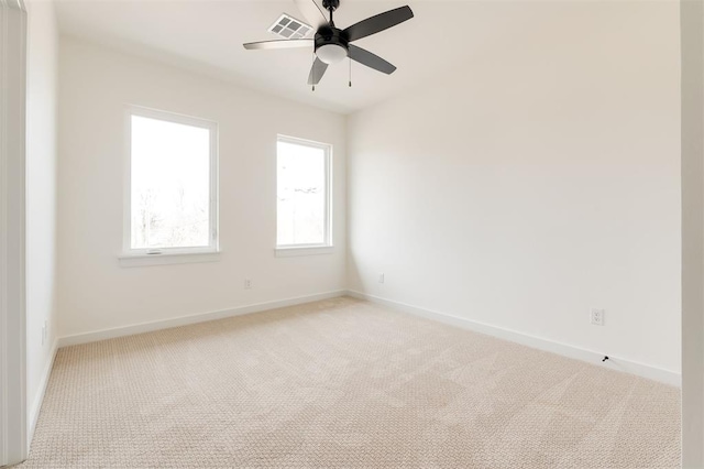 unfurnished room with visible vents, baseboards, light colored carpet, and ceiling fan