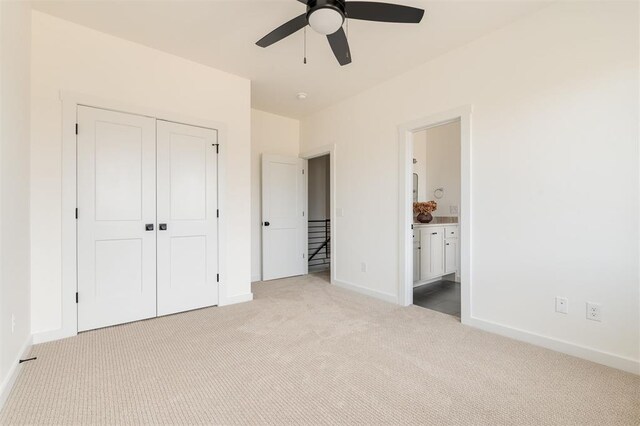 unfurnished bedroom with a ceiling fan, baseboards, a closet, light carpet, and connected bathroom