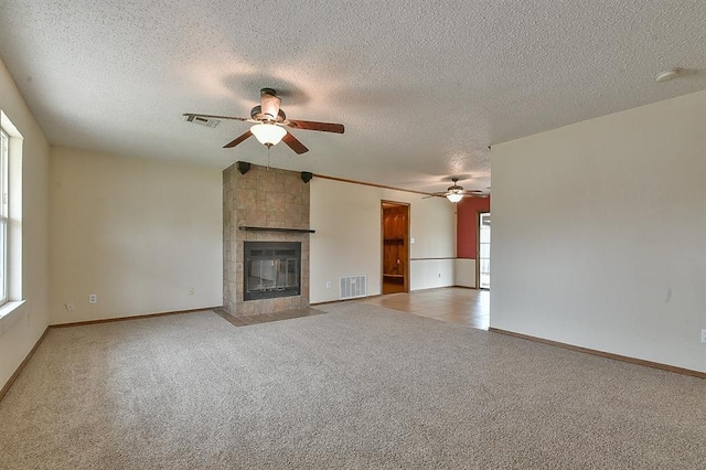 unfurnished living room with visible vents, ceiling fan, a tile fireplace, and carpet