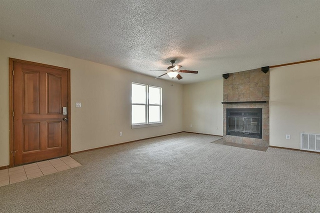 unfurnished living room with a ceiling fan, visible vents, a tile fireplace, a textured ceiling, and light colored carpet