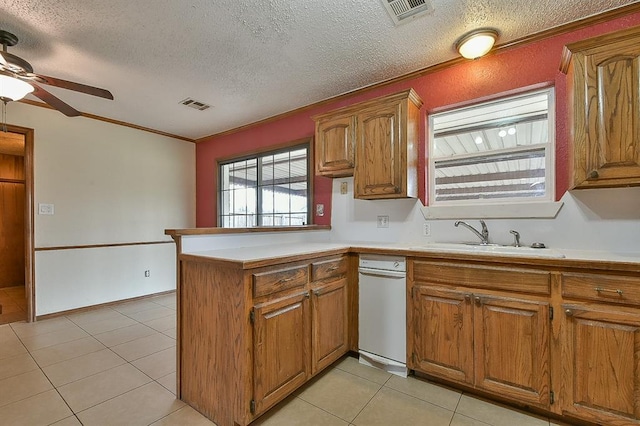 kitchen with brown cabinetry, visible vents, a peninsula, and a sink