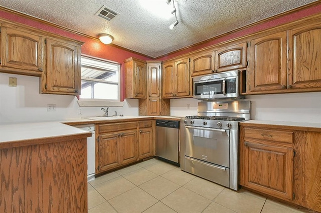 kitchen with stainless steel appliances, a textured ceiling, visible vents, and brown cabinetry