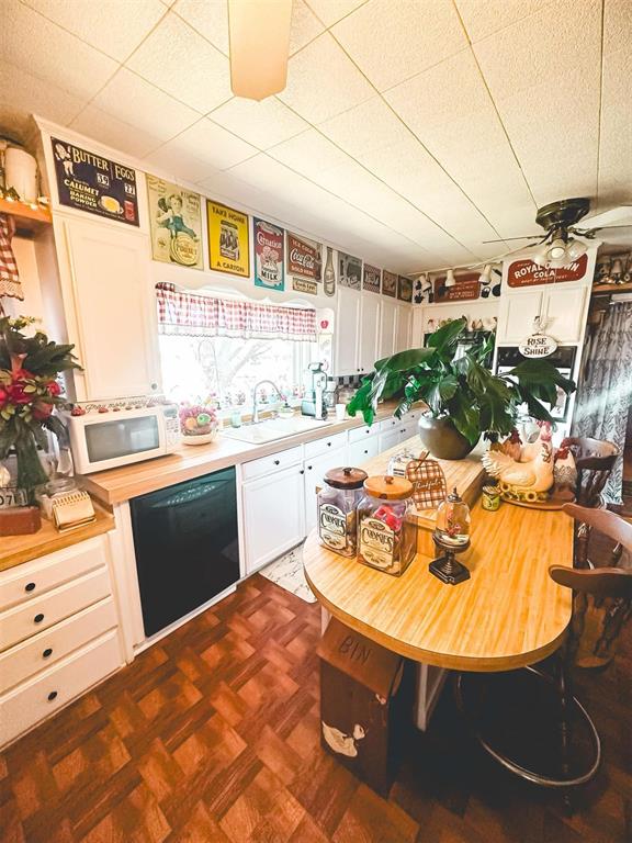 kitchen with a ceiling fan, a sink, white cabinetry, white microwave, and dishwasher