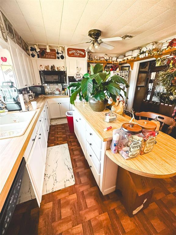 kitchen with a sink, black dishwasher, white cabinetry, butcher block counters, and ceiling fan