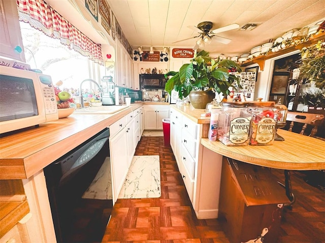 kitchen with white microwave, visible vents, black dishwasher, white cabinets, and a sink