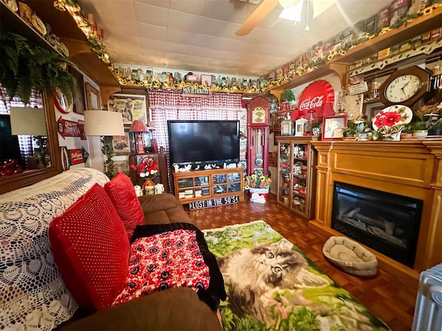 living area with a glass covered fireplace and a ceiling fan