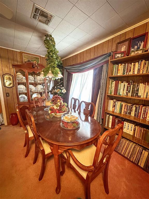 dining area with visible vents, light colored carpet, and wooden walls