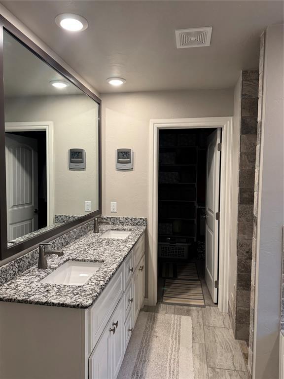 bathroom with double vanity, recessed lighting, visible vents, and a sink