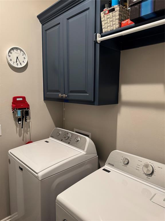 washroom featuring cabinet space and washer and clothes dryer