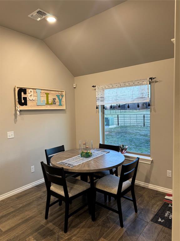 dining space featuring visible vents, dark wood-style flooring, baseboards, and vaulted ceiling