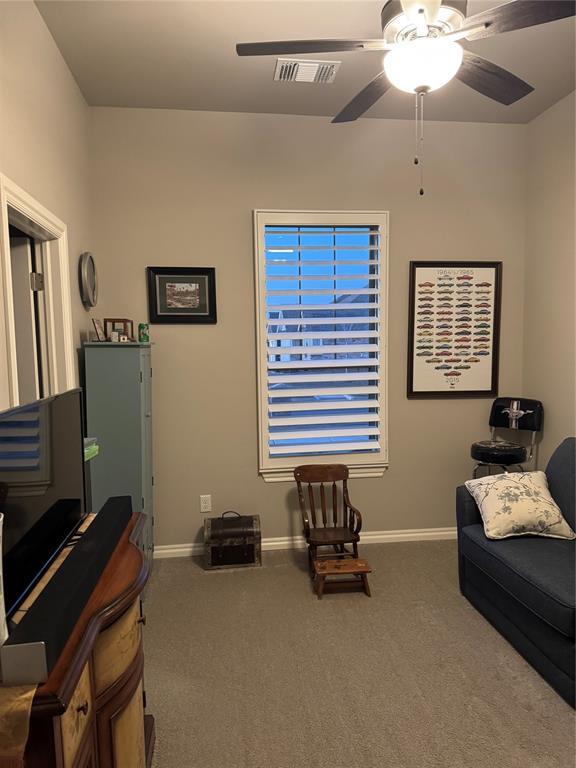 living area featuring a ceiling fan, carpet, visible vents, and baseboards