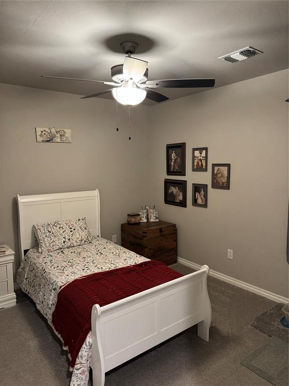 bedroom with baseboards, visible vents, dark carpet, and ceiling fan