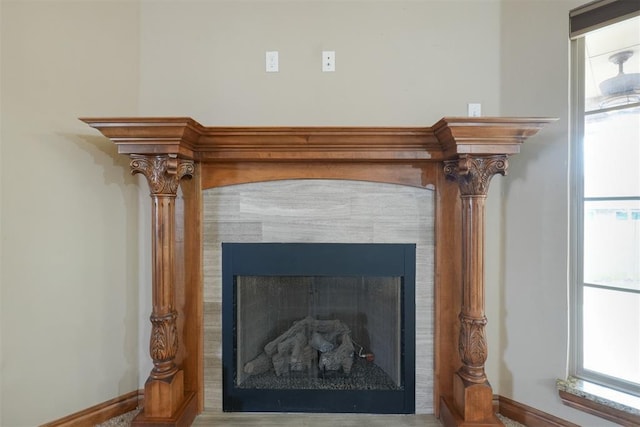 interior details with a tiled fireplace and baseboards