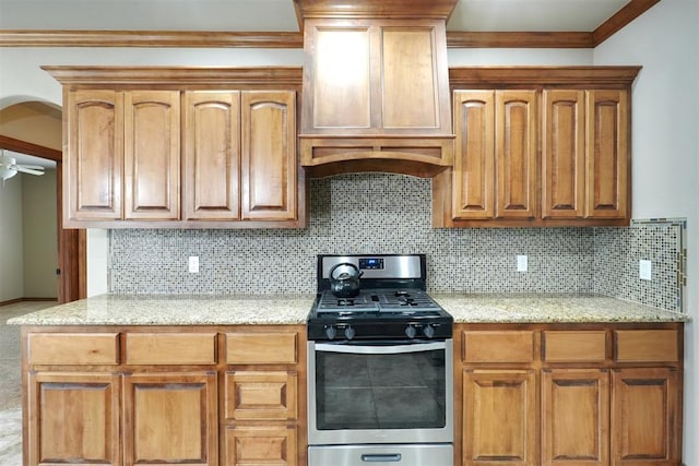 kitchen with light stone counters, gas stove, tasteful backsplash, and crown molding