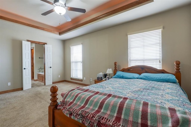 bedroom featuring ensuite bath, a tray ceiling, carpet, and baseboards