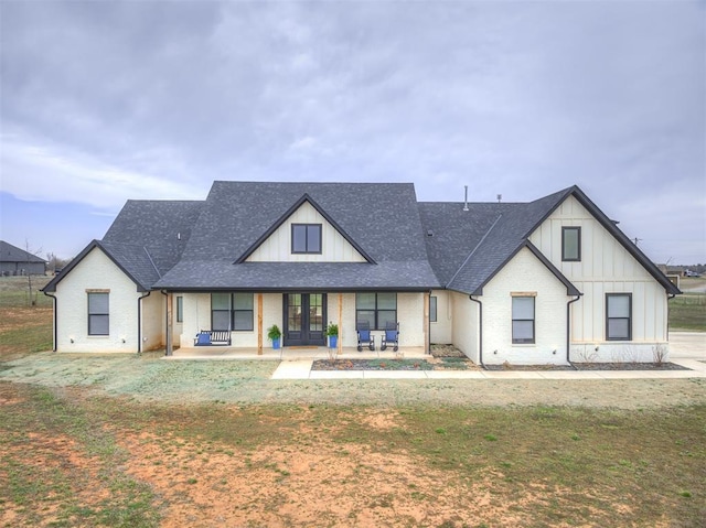 19000 Bobcat Ridge Ct, Cashion, OK 73016 - view of front facade with french doors, a shingled roof, board and batten siding, and a front lawn