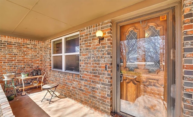 doorway to property featuring brick siding and a porch