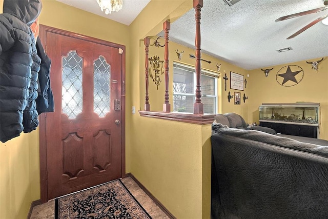 entryway with visible vents, baseboards, light tile patterned floors, a textured ceiling, and a ceiling fan