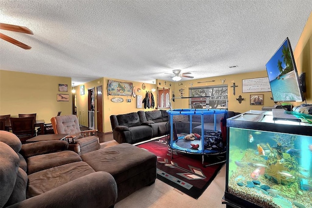 living area featuring carpet, ceiling fan, and a textured ceiling