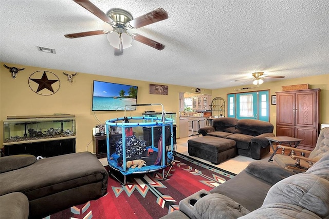 living area featuring a ceiling fan, visible vents, carpet floors, and a textured ceiling