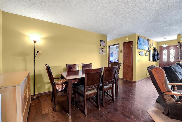 dining room with a notable chandelier, a textured ceiling, dark wood-type flooring, and baseboards