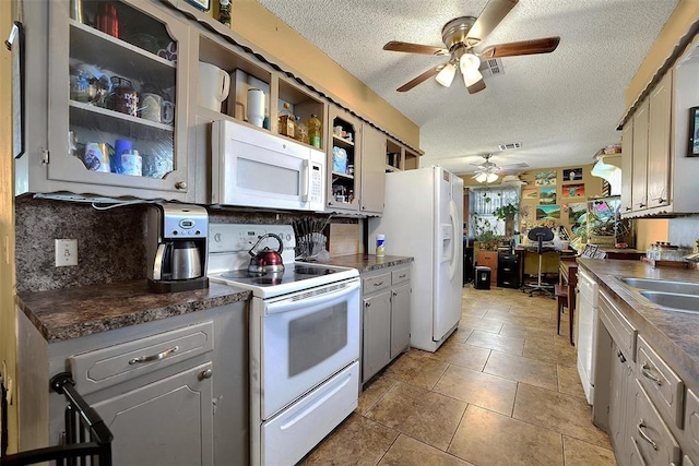 kitchen with white appliances, dark countertops, open shelves, and a sink