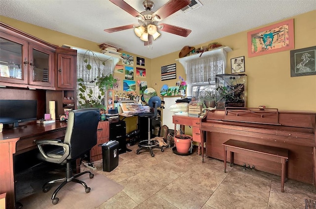 office space with a textured ceiling, visible vents, and ceiling fan