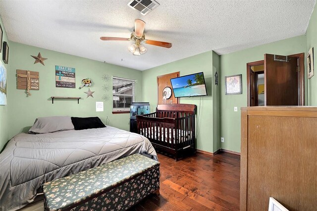 bedroom with visible vents, baseboards, wood finished floors, a textured ceiling, and a ceiling fan