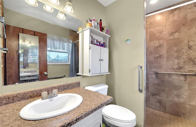 full bathroom with a tile shower, toilet, and vanity