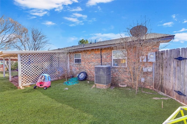 back of house with brick siding, central AC unit, a lawn, and fence