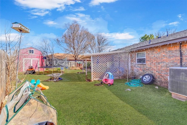 view of yard featuring an outbuilding, central AC, and a trampoline