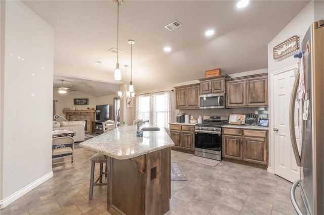 kitchen featuring visible vents, lofted ceiling, a sink, stainless steel appliances, and open floor plan