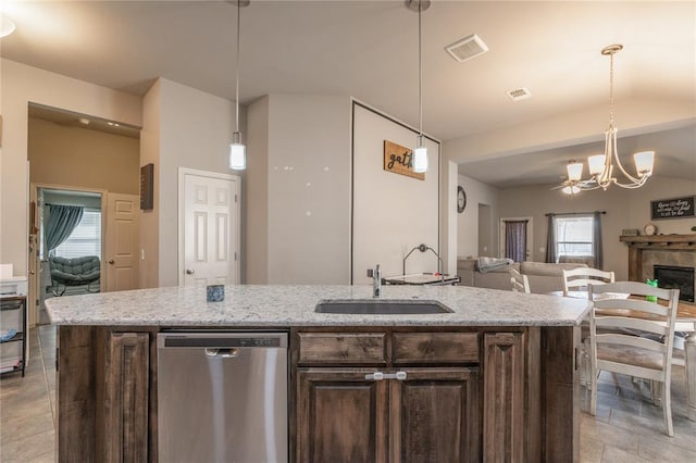 kitchen with dark brown cabinets, open floor plan, stainless steel dishwasher, an inviting chandelier, and a sink