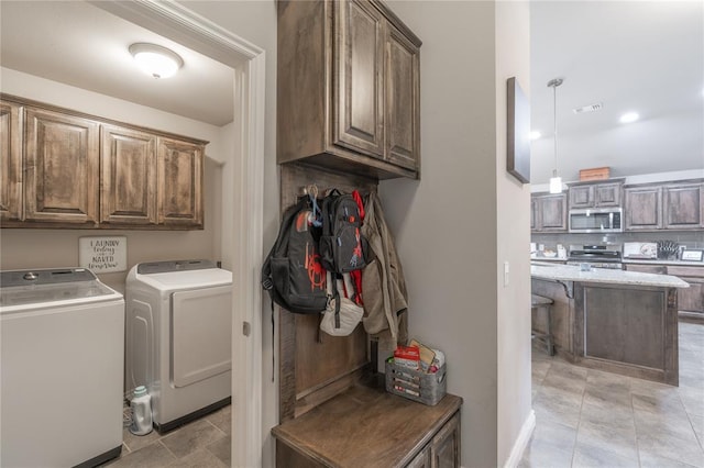 clothes washing area featuring cabinet space, visible vents, and washer and dryer